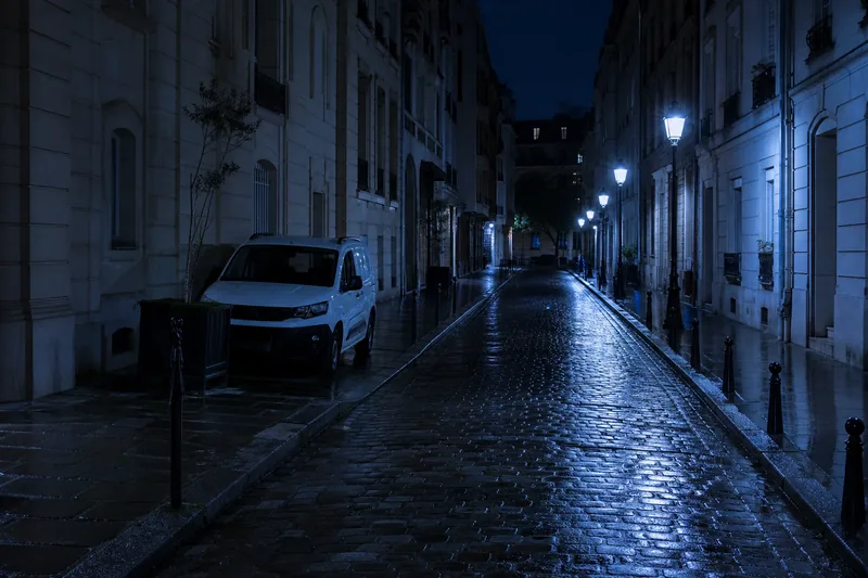 Rue d’une ville française la nuit, camionnette garée devant un immeuble